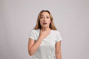 Young woman suffering from pain during breathing on light grey background