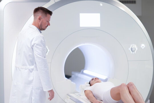 Doctor standing near patient lying in mri machine in clinic