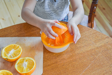 the child girl in the kitchen cuts and squeezes oranges juice