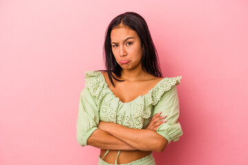 Fototapeta premium Young latin woman isolated on pink background shrugs shoulders and open eyes confused.