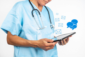 EIne Ärztin mit einem Tablet PC in den Händen aus dem viele Social Media Symbolen für Emails und...