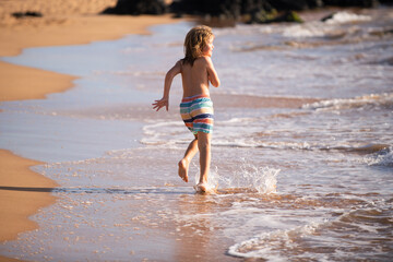Active little boy splashing in the sea waves on a summer day during the holidays. The concept of family holidays with children.