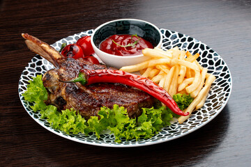 Lamb rack with fries and sauce. On a wooden background