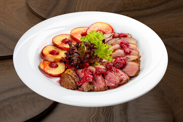 Duck breast mangre with berry confit and baked apple.  On a wooden background