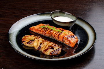 Salmon with cream sauce and grilled pineapple. On a wooden background