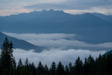 wonderful view in the morning with fog in the valley and a cloudy sky on the mountains