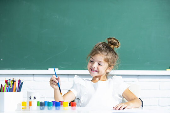 Funny school girl pupil drawing a picture. Cute little preschooler child drawing at school.