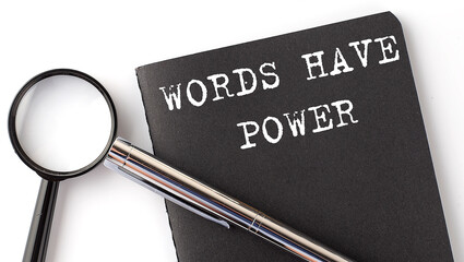 WORDS HAVE POWER - business concept, magnifier with white text message on black notebook