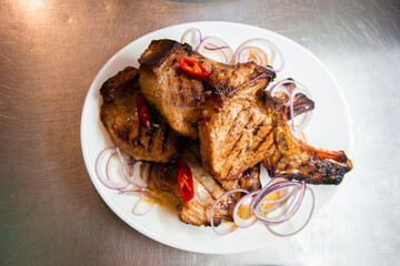 BBQ grill ribs served in portions in the restaurant kitchen. Plates with meat dish close-up, studio. 