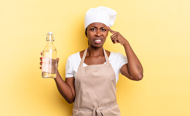 black afro chef woman feeling confused and puzzled, showing you are insane, crazy or out of your...