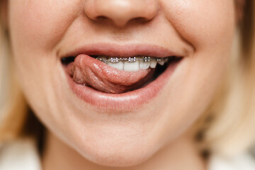 Young woman smiling while licking her brace indoors