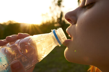 woman drinking water from a bottle face closeup summer
