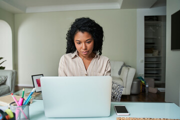 Fototapeta na wymiar Multiracial woman wearing domestic clothes looking at the laptop screen