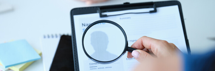 Employee examines resume application form under magnifying glass