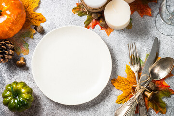 Thanksgiving food. Autumn table setting with white plate, silverware and fall decorations at stone table. Top view with copy space.