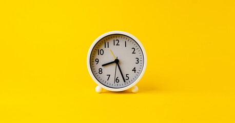 white alarm clock The clock tells the time to wake up in the morning. placed on a yellow background