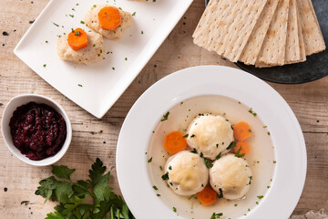 Traditional Jewish matzah ball soup, gefilte fish and matzah bread on wooden table	