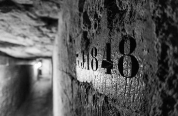 Numbers engraved on the wall of the catacombs of Paris in focus, with the background out of focus. In black and white