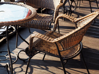 Sunlit wicker chairs sit at the table on a wooden veranda. Street Cafe