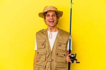 Young fisherman with makeup holding rod isolated on yellow background  happy, smiling and cheerful.