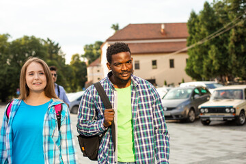 Two friends with backpacks walking and talking outdoors