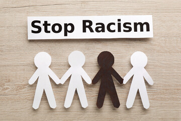 Phrase Stop Racism and paper figures on wooden table, flat lay