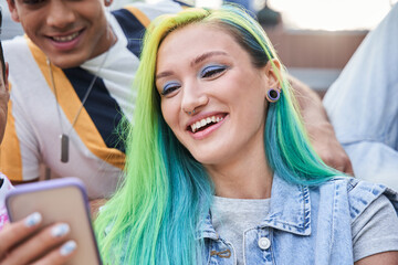 Teen girl with color hair looking at the smartphone screen with happy smile
