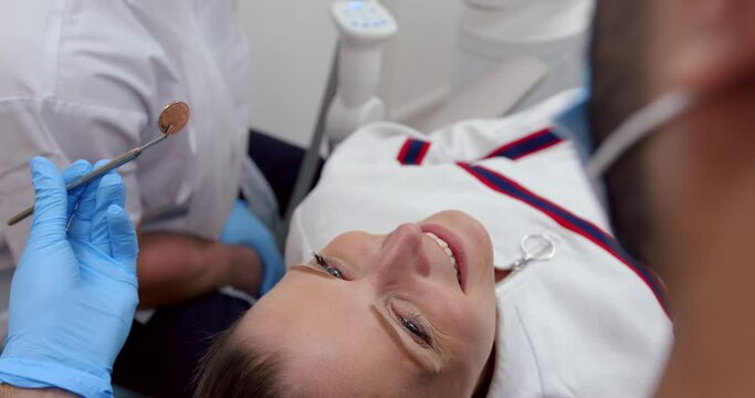 Caucasian female patient smiling at doctor while male nurse exams teeth before cleaning process