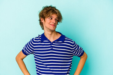 Young caucasian man with make up isolated on blue background  confused, feels doubtful and unsure.