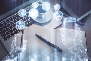 Technology hologram drawing over computer on the desktop background. Top view. Double exposure. Tech concept.