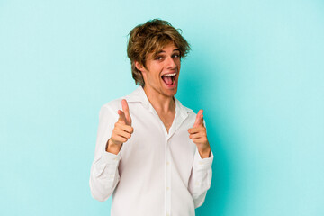 Young caucasian man with make up isolated on blue background  pointing to front with fingers.