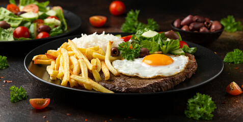 Portugal dish Bitoque made from beef steak with a fried egg, rice, french fries and vegetables - obrazy, fototapety, plakaty