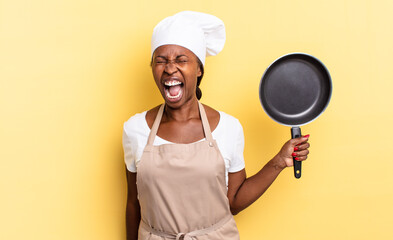 black afro chef woman shouting aggressively, looking very angry, frustrated, outraged or annoyed,...