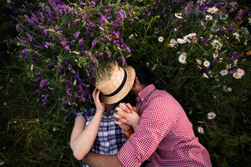 Romantic couple embracing in summer field with blooming wildflowers