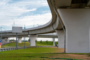 View of highway overpass curved approach bridge in city. City road viaduct streetscape on cloudy day