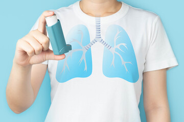 Young woman using blue asthma inhaler for relief asthma attack. Pharmaceutical products is used to...