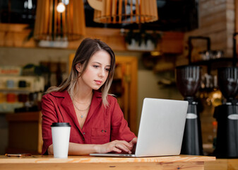 young woman using laptop computer drink a coffee sits at table in a cafe