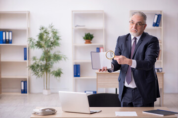 Old male employee sitting at workplace