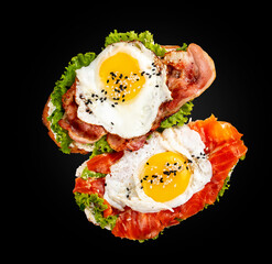 Toast with salmon, bacon and cream cheese.  On a black background. Breakfast