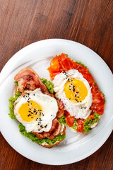 Toast with salmon, bacon and cream cheese.  On a wooden background. Breakfast