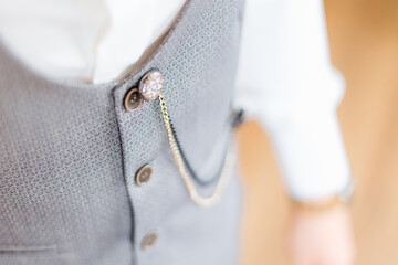 The groom in a stylish gray waistcoat and white shirt with a cha