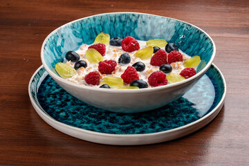 Oatmeal porridge with seasonal berries. On a wooden background. Breakfast