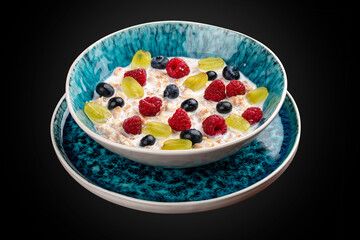 Oatmeal porridge with seasonal berries. On a dark background. Breakfast