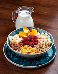 Muesli with banana, nuts, peach and raspberries. On a wooden background. Breakfast