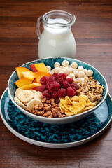 Muesli with banana, nuts, peach and raspberries. On a wooden background. Breakfast