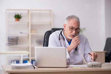 Obraz premium Old male doctor working in the clinic