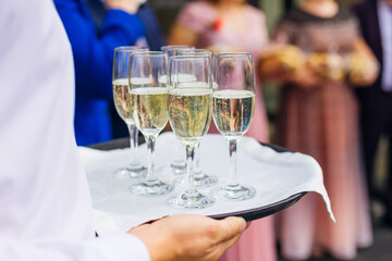 Catering service waiter holding a tray with glasses of Italian and French wine prosecco and champagne for tasting
