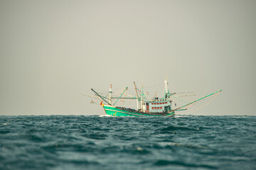 Traditional Thai fishing boat painted in green white sailing through Andaman Sea waters