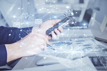 Double exposure of man's hands holding and using a digital device and envelop hologram drawing. E-mail concept.