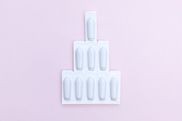 Gynecological medicines for women's health in form of suppository, capsules on pink background.